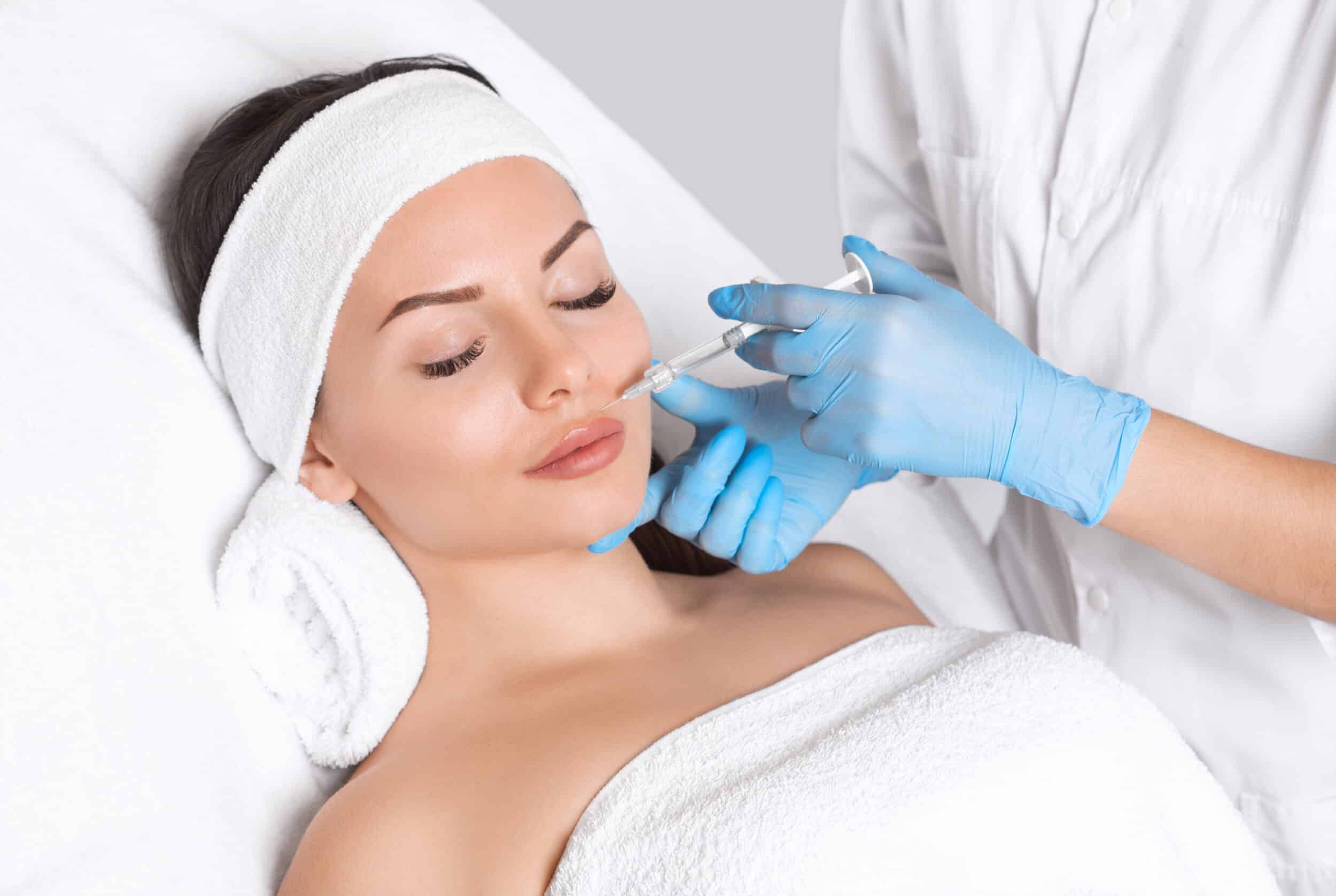 Woman rests peacefully, smiling during dermal filler treatment